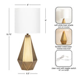 Geometric faceted metal table lamp base with polished brass finish topped by a soft white linen cylindrical shade, shown with dimensions and clear cord with toggle switch.