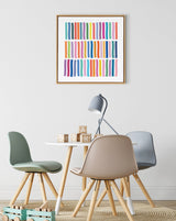 Abstract framed canvas featuring colorful vertical wavy lines in orange, blue, green, pink, and purple above a round white table with pastel green, beige, and gray chairs and a modern gray desk lamp.