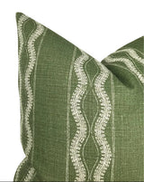 Green fabric pillow cover with vertical white wavy line patterns and subtle horizontal thread texture, showing a close-up of a corner and part of the front panel.