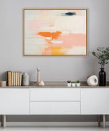 Abstract canvas by Amy Lighthall with soft peach, orange, yellow, and white horizontal brush strokes accented by thin linear details, displayed above a minimalist cabinet with decor.