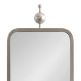 Rectangular mirror with rounded top corners in a textured metal frame topped by a large and small silver metal sphere on a vertical rod.