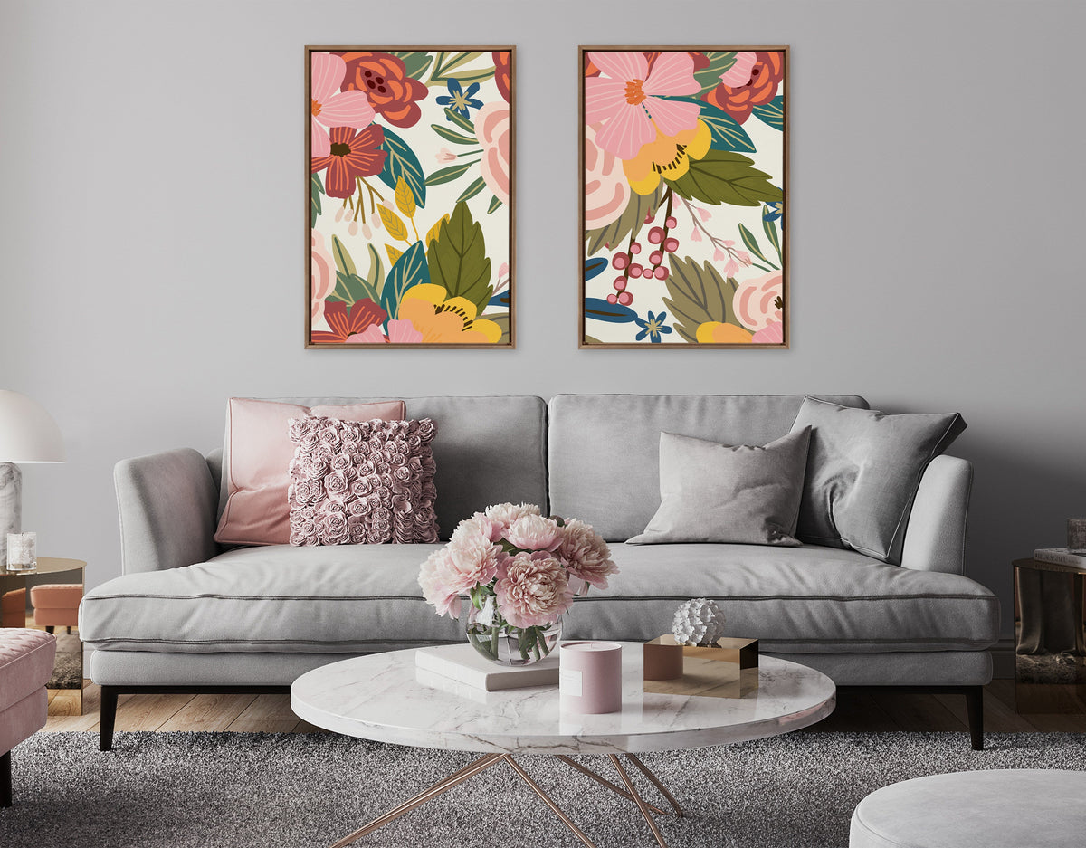 Two framed canvases with colorful floral artwork hung above a light gray sofa with textured cushions in a modern living room setting.
