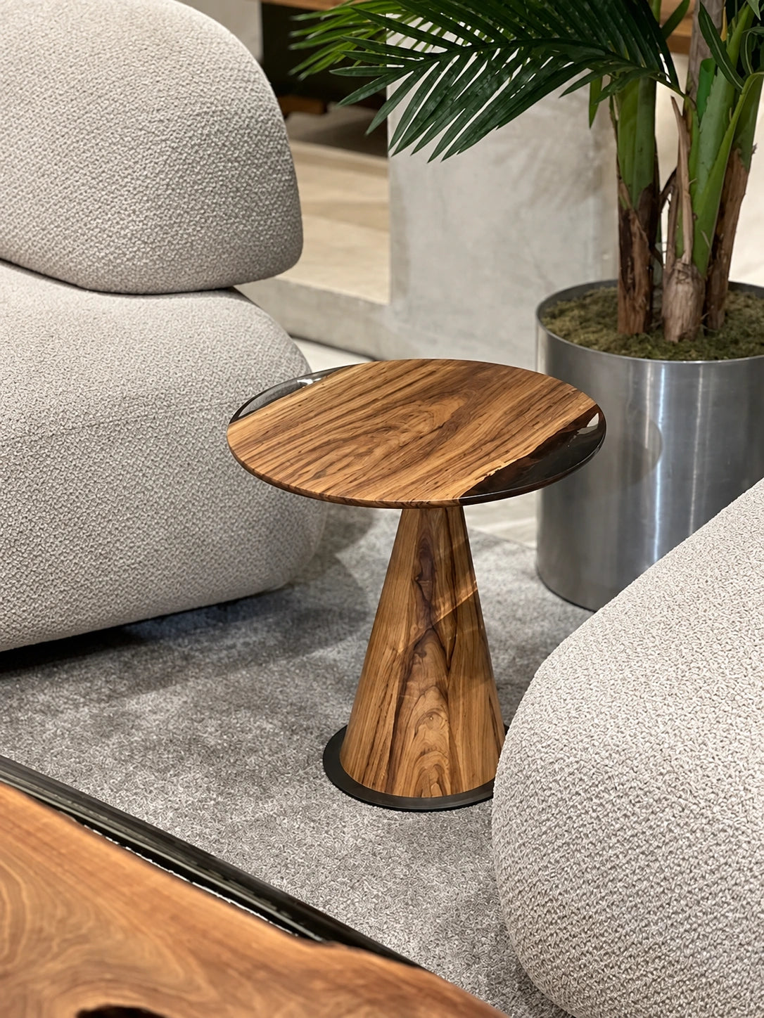 Walnut and clear-resin mushroom table beside upholstered seating.